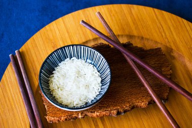 Asya sofra takımı, çiğ pirinç, kase ve yemek çubukları, ahşap malzeme, seramik kase. Pirinç tohumları.