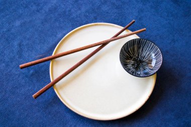 Boş Asyalı bulaşık takımı, kase, ezme ve yemek çubukları mavi arka planda, restoran sofra takımı