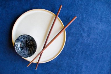 Boş Asyalı bulaşık takımı, kase, ezme ve yemek çubukları mavi arka planda, restoran sofra takımı