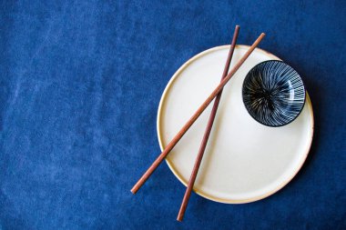 Boş Asyalı bulaşık takımı, kase, ezme ve yemek çubukları mavi arka planda, restoran sofra takımı