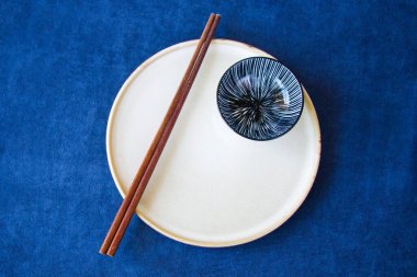 Boş Asyalı bulaşık takımı, kase, ezme ve yemek çubukları mavi arka planda, restoran sofra takımı