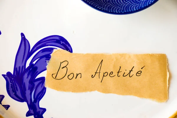 Empty blue tableware, paper and Bon apetite letter and text. Blue colors.