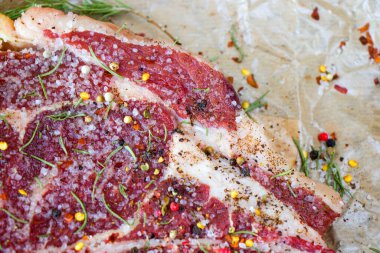 Masada çiğ et, baharat ve biberiye, biftek malzemeleri. Biber ve kola tuzu. Doğal ışık.