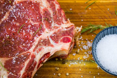 Masada çiğ et, baharat ve biberiye, biftek malzemeleri. Biber ve kola tuzu. Doğal ışık.