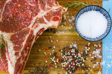 Masada çiğ et, baharat ve biberiye, biftek malzemeleri. Biber ve kola tuzu. Doğal ışık.