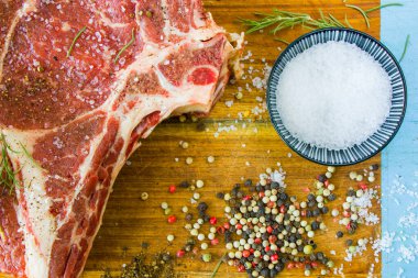 Masada çiğ et, baharat ve biberiye, biftek malzemeleri. Biber ve kola tuzu. Doğal ışık.