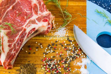 Masada çiğ et, baharat ve biberiye, biftek malzemeleri. Biber ve kola tuzu. Doğal ışık.