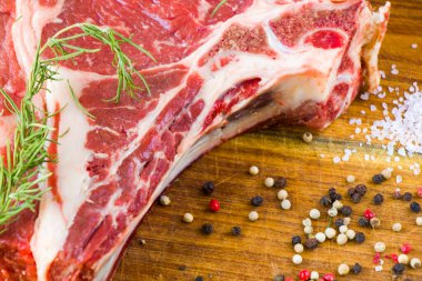 Masada çiğ et, baharat ve biberiye, biftek malzemeleri. Biber ve kola tuzu. Doğal ışık.