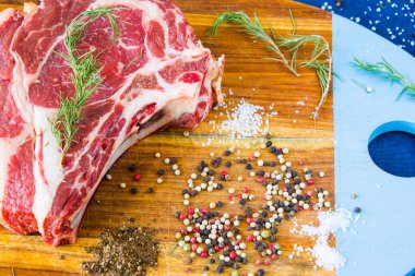 Masada çiğ et, baharat ve biberiye, biftek malzemeleri. Biber ve kola tuzu. Doğal ışık.