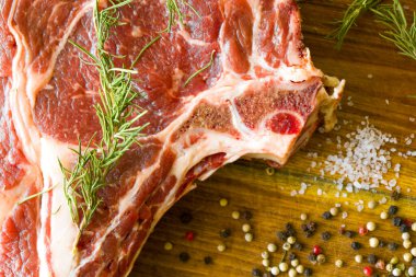 Masada çiğ et, baharat ve biberiye, biftek malzemeleri. Biber ve kola tuzu. Doğal ışık.