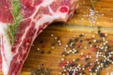 Masada çiğ et, baharat ve biberiye, biftek malzemeleri. Biber ve kola tuzu. Doğal ışık.