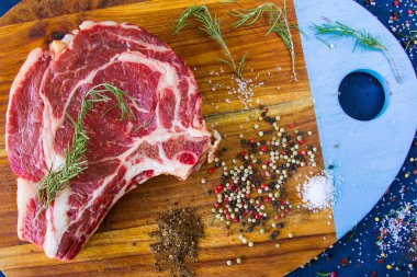 Masada çiğ et, baharat ve biberiye, biftek malzemeleri. Biber ve kola tuzu. Doğal ışık.