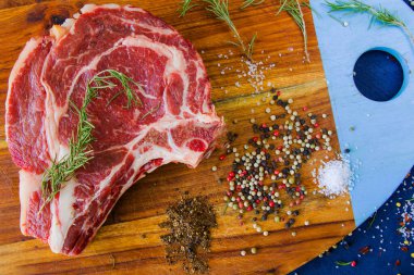 Masada çiğ et, baharat ve biberiye, biftek malzemeleri. Biber ve kola tuzu. Doğal ışık.