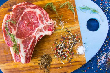 Masada çiğ et, baharat ve biberiye, biftek malzemeleri. Biber ve kola tuzu. Doğal ışık.