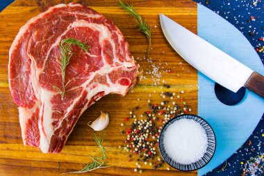 Masada çiğ et, baharat ve biberiye, biftek malzemeleri. Biber ve kola tuzu. Doğal ışık.