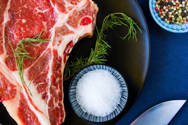 Masada çiğ et, baharat ve biberiye, biftek malzemeleri. Biber ve kola tuzu. Doğal ışık.