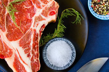 Masada çiğ et, baharat ve biberiye, biftek malzemeleri. Biber ve kola tuzu. Doğal ışık.