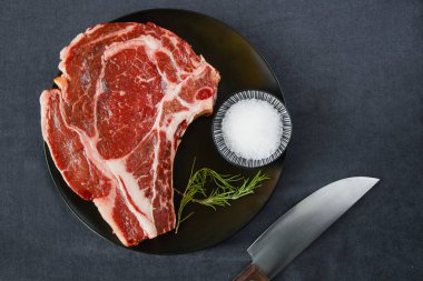 Masada çiğ et, baharat ve biberiye, biftek malzemeleri. Biber ve kola tuzu. Doğal ışık.