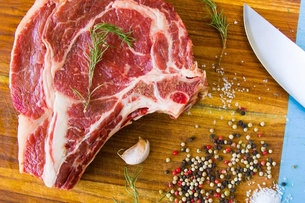 Masada çiğ et, baharat ve biberiye, biftek malzemeleri. Biber ve kola tuzu. Doğal ışık.