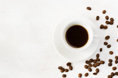 Beyaz arka planda kahve fincanında espresso ve kahve çekirdeği.