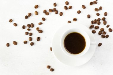 Beyaz arka planda kahve fincanında espresso ve kahve çekirdeği.
