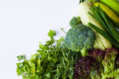 Beyaz arka planda yeşil sebze yaprakları, çiğ tarhun, kabak, lahana ve salatalık.