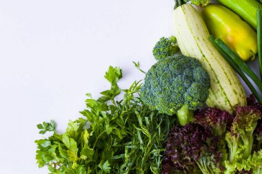 Beyaz arka planda yeşil sebze yaprakları, çiğ tarhun, kabak, lahana ve salatalık.