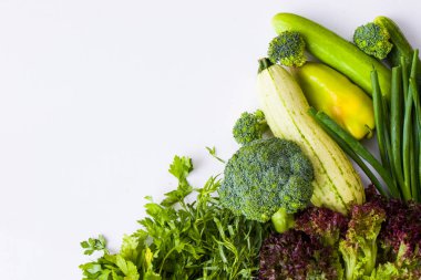 Beyaz arka planda yeşil sebze yaprakları, çiğ tarhun, kabak, lahana ve salatalık.