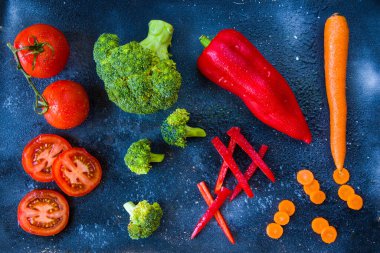 Tahtada doğranmış ve kesilmiş sebzeler, havuç, dolma biber, domates ve brokoli.