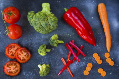 Tahtada doğranmış ve kesilmiş sebzeler, havuç, dolma biber, domates ve brokoli.