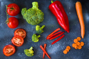 Tahtada doğranmış ve kesilmiş sebzeler, havuç, dolma biber, domates ve brokoli.