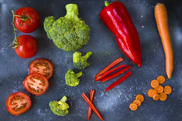 Tahtada doğranmış ve kesilmiş sebzeler, havuç, dolma biber, domates ve brokoli.