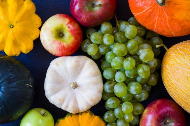 Sonbahar ve sonbahar hasadı, balkabağı, elma, üzüm ve pattison mavi arka planda.