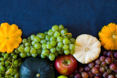 Sonbahar ve sonbahar hasadı, balkabağı, elma, üzüm ve pattison mavi arka planda.