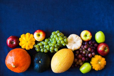 Sonbahar ve sonbahar hasadı, balkabağı, elma, üzüm ve pattison mavi arka planda.