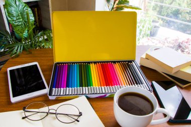 Çizim masası, kalem ve çizim defteri, boş kağıt ve renkli kalemler.