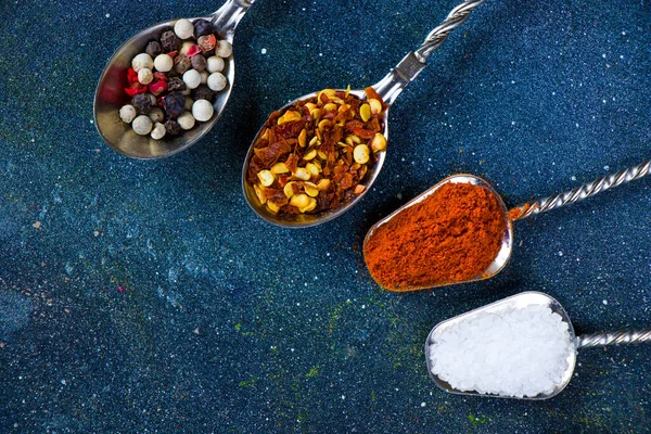 variation of spices on the vintage silver spoons, all spices on the table, colorful food background