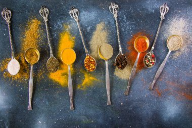 Eski gümüş kaşıklardaki baharat çeşitleri, masadaki tüm baharatlar, renkli yemek arkaplanı.