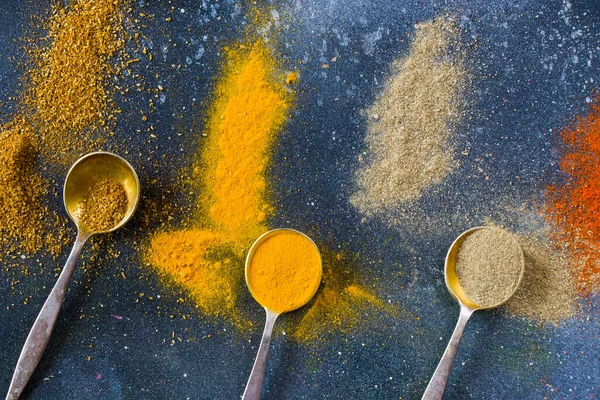 variation of spices on the vintage silver spoons, all spices on the table, colorful food background