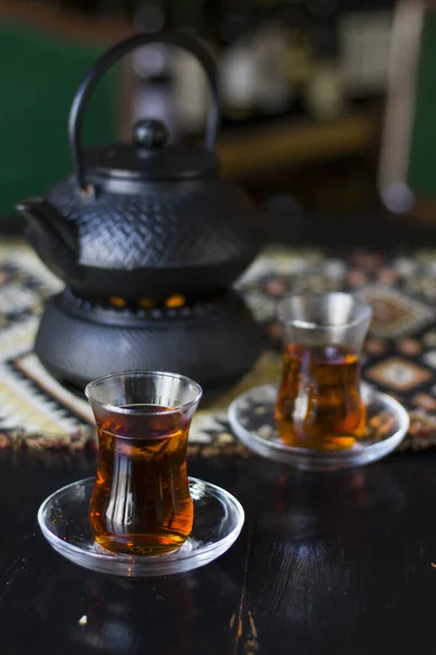 Black tea and teapot in hand, Turkish tea glasses and old iron teapot