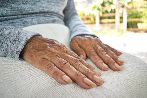 The hand of the sick old woman rests on the lap. Mental health care at home.