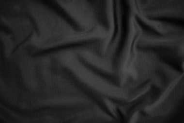 Arkaplan dokusu siyah kumaş. Soyut koyu dalgalı yumuşak. Kumaş kırışmış. Lüks moda tarzı..