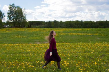 Parlak elbiseli bir kız yazın tarlada yürür.