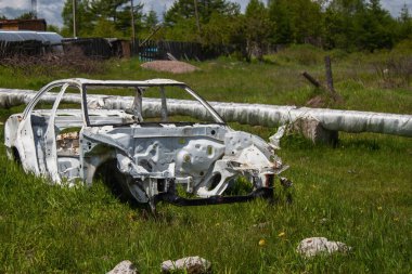 Beyaz araba iskeleti, yanan boruların arasında çöp atılıyor.