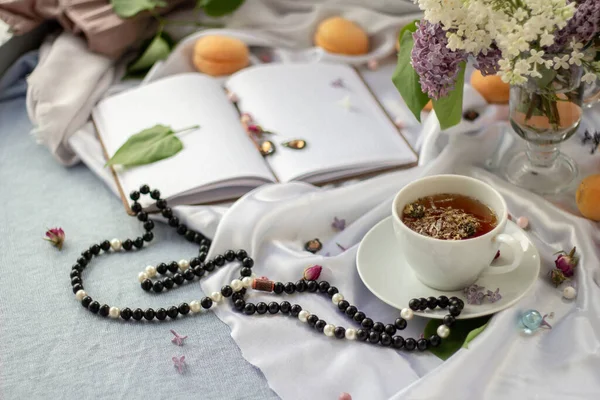 Delicate still life of peaches, lilacs of tea and beads