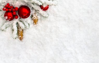 Noel süsü. Ağaç dalları, noel baloları, böğürtlenler ve kozalaklar karların üzerinde. Üst manzara, düz uzanma