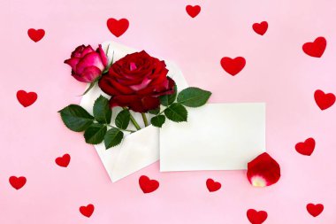 Sevgililer Günü 'nün dekorasyonu. Güzel çiçekler posta zarfında kırmızı güller ve yazı için boşluk ve pembe kağıtta kırmızı yaprak.