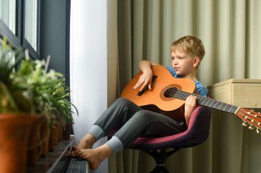 Akustik gitar çalan bir çocuk.  