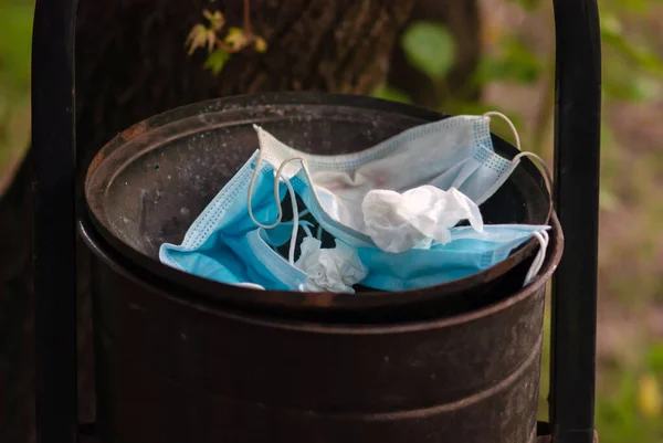 face masks and used antibacterial wipes thrown into trash bin outdoors