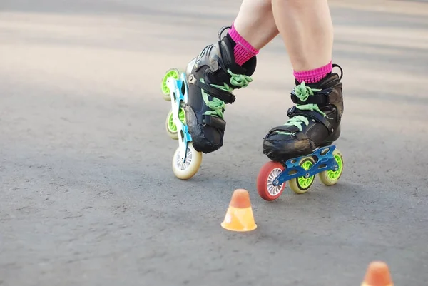 Hareket halindeki patenci bacakları, inline paten kayma, paten kayma, asfalt yüzeyde slalom. Yolda eğitim için küçük külahlar..